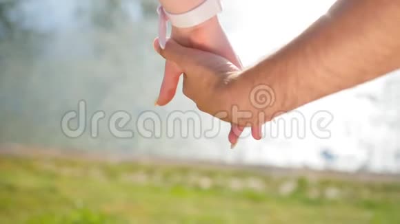 当幸福的一对夫妇站在公园附近时一位年轻男子牵着一位年轻女子的手浪漫的特写镜头视频的预览图