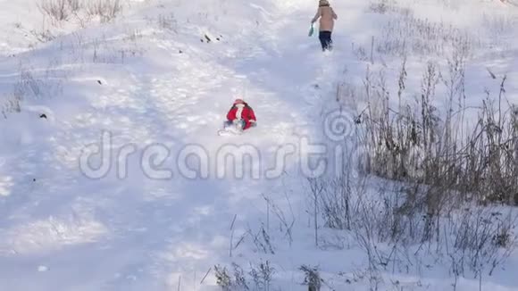 快乐的孩子骑着雪橇坐着白雪覆盖的高过山车雪溅到女孩脸上家庭圣诞节视频的预览图