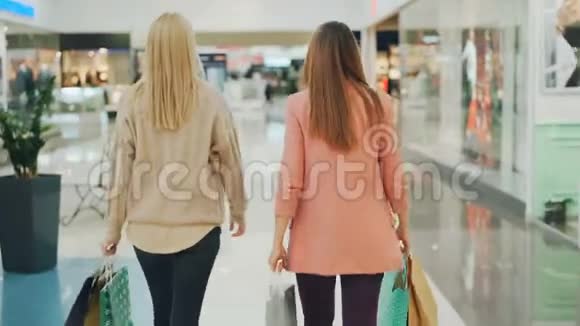 后镜头中纤细的年轻女性在商场里拿着纸袋环顾四周快乐视频的预览图
