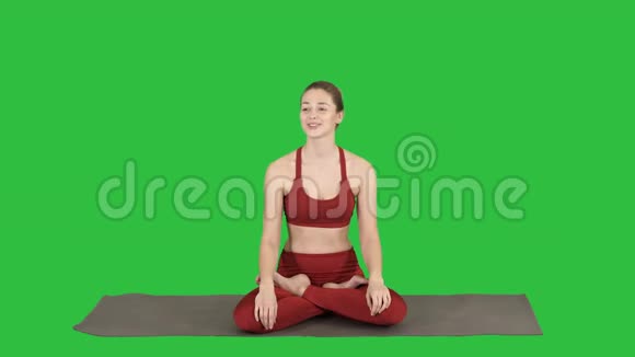 美丽的女人坐在瑜伽垫上和一个绿色屏幕上的人交谈铬钥匙视频的预览图