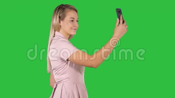 年轻漂亮的女人在手机上的绿色屏幕上自拍Chroma键视频的预览图