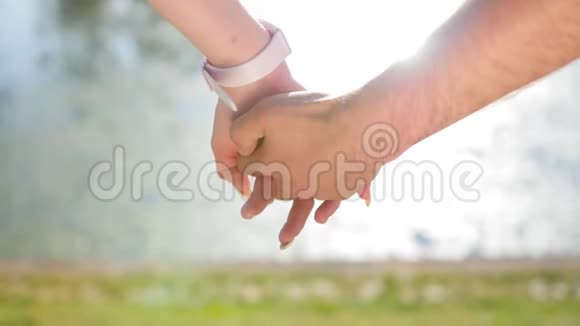 当幸福的一对夫妇站在公园附近时一位年轻男子牵着一位年轻女子的手浪漫的特写镜头视频的预览图