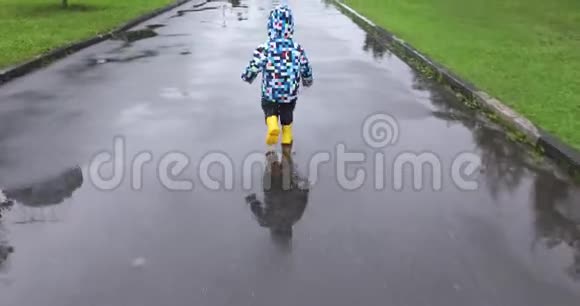 可爱的小男孩在水坑里奔跑视频的预览图
