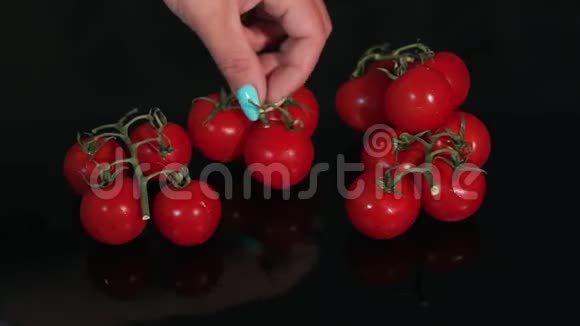 特写女孩把樱桃番茄放在黑色的镜子背景上慢动作视频的预览图