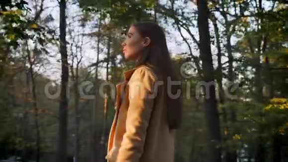 美丽的白种女人在美丽的秋天公园散步以大自然树木为背景快乐地拍照视频的预览图