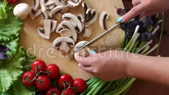 一个女人在木制砧板上切蘑菇的特写上景视频的预览图