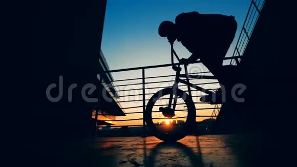 一个骑自行车的人在日落后路上跳动作缓慢视频的预览图