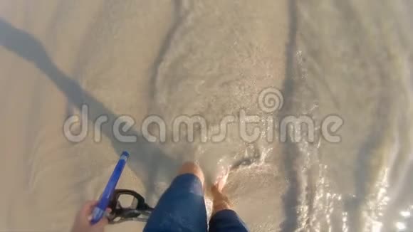 一个手拿着浮潜面罩在海浪中行走的人的超慢镜头视频的预览图