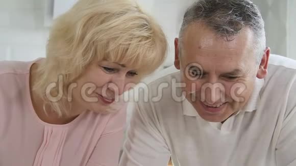 美国男人和女人坐在办公桌前玩电话玩得很开心视频的预览图