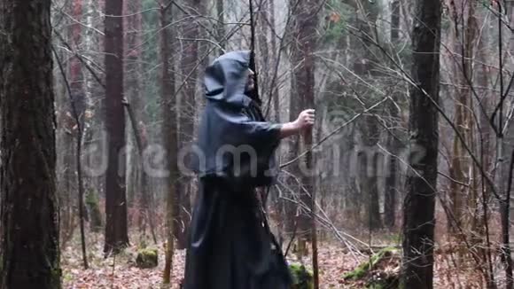 一个穿着黑色长袍的和尚带着一个杖穿过森林一个穿着的游荡的德鲁伊穿过丛林视频的预览图