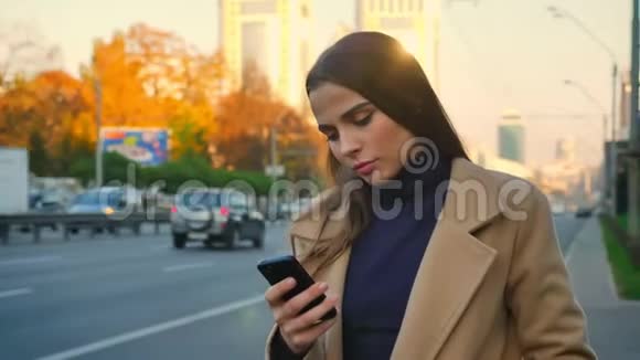 在电话中白种人女孩非常专注她站在路边开车静静地等待交通视频的预览图