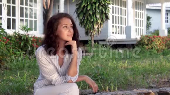 一个年轻漂亮体贴的女人坐在她乡下房子的门廊上视频的预览图