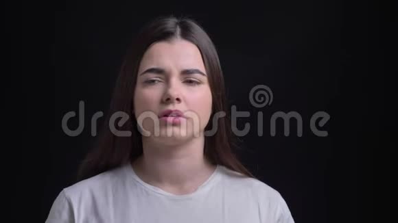 年轻的超重的黑发白种人女孩喉咙痛和触摸她的脖子在黑色背景的肖像视频的预览图