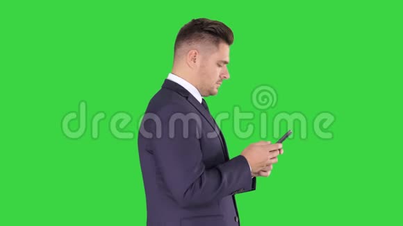 成熟的商人使用手机短信在绿色屏幕上色度键视频的预览图