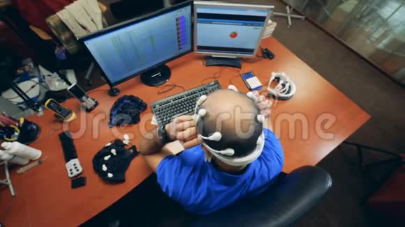 一个男人坐着戴上生物信号脑电图耳机的俯视图视频的预览图