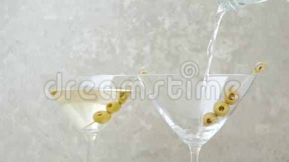 豪华马提尼手把甜马提尼倒入空杯中桌上用橄榄和鸡尾酒棒装饰着橄榄视频的预览图