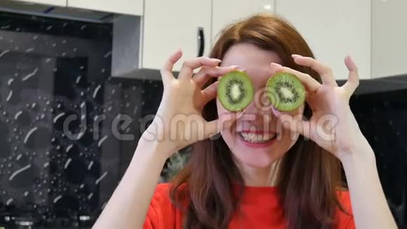 在厨房准备食物的时候一个疯狂的年轻女孩在她的眼睛上露出猕猴桃积极的人类情感概念视频的预览图
