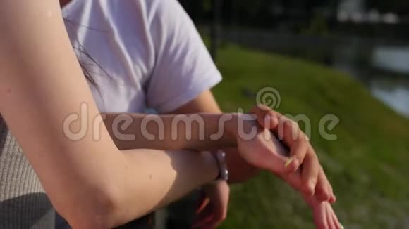 当幸福的一对夫妇站在公园附近时一年轻男子牵着一位年轻女子的手的浪漫特写视频的预览图