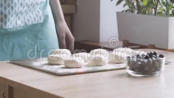 女厨师烹饪芝士蛋糕西尼基传统俄罗斯薄饼从家庭奶酪和蓝莓在桌子上慢动作视频的预览图