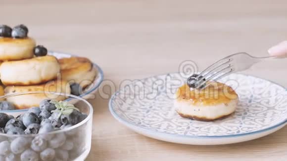 女厨师切切芝士蛋糕西尼基传统俄罗斯薄煎饼从家庭干酪和蓝莓在桌子上视频的预览图