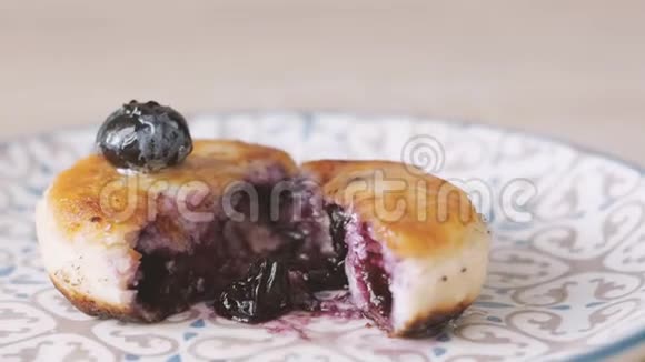 女性用手把一片薄荷叶放在sirniki传统的俄式薄饼上上面有白干酪和蓝莓视频的预览图