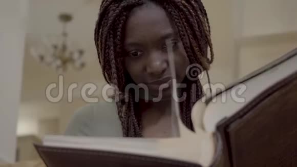 美丽的微笑带着恐惧的非裔美国女人光着身子看着大皮革背相册里的照片视频的预览图