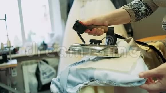 一个女人的手在木板上敲打专业的铁纺织品专业蒸衣服视频的预览图