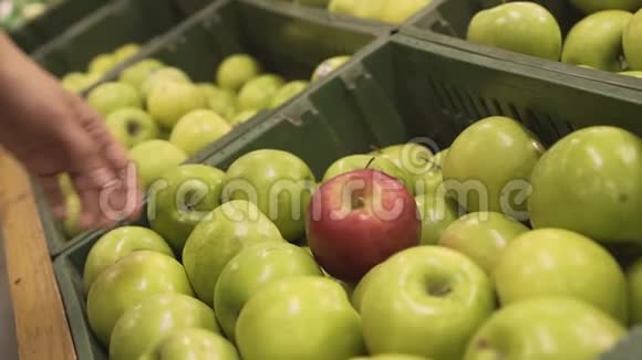 在一家超市的熟食店里在出售的青苹果中挑选红苹果的女性手特写视频的预览图