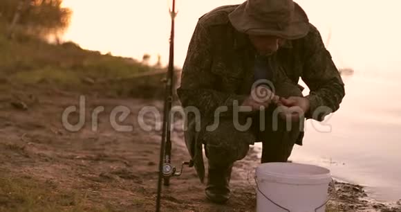 一个老渔夫抓着一条虫子发霉的虫子在钓竿钩上视频的预览图