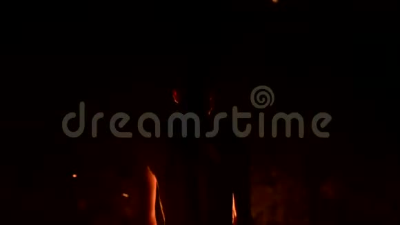特写后景低调黑色的夜晚年轻的男性长发裸露的躯干在室外旋转燃烧的火炬视频的预览图