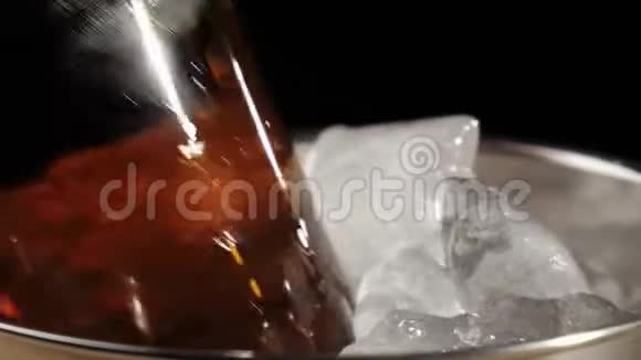 新鲜啤酒手拿一个棕色的瓶子和美味的工艺啤酒从一个桶里拿出来在黑色的背景下放着冰冷的真正的冰视频的预览图