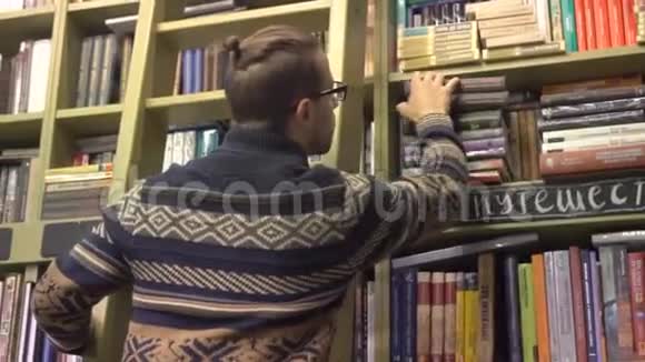 图书馆里的一个年轻人爬上楼梯在书架上找一本书视频的预览图