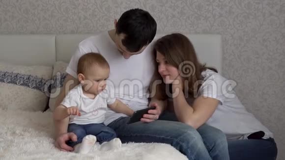 一个女孩和父母在床上通过电话看动画片视频的预览图