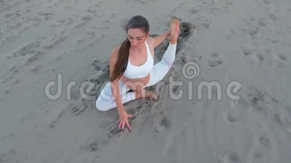 年轻女子正在日出时在沙滩上做瑜伽鸽子视频的预览图