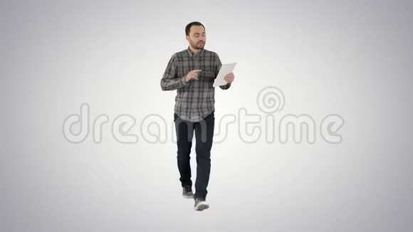 漫不经心地拿着平板电脑走路在梯度背景下通过视频会议聊天的男人视频的预览图