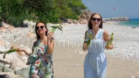 年轻漂亮快乐的女人手里拿着玉米在海滩上跳着滑稽的舞蹈视频的预览图