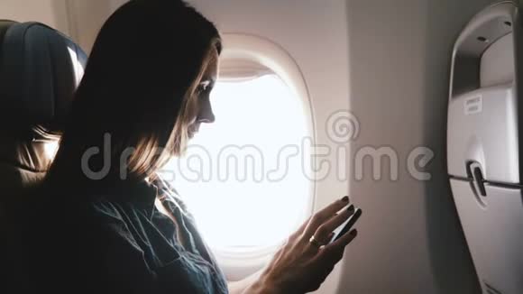 在飞机飞行期间使用智能手机移动办公应用程序特写漂亮放松的白人年轻快乐女商人视频的预览图