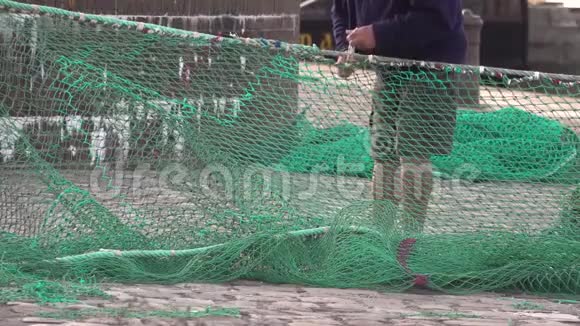 一名港口工人正在外面固定一张绿色尼龙渔网视频的预览图