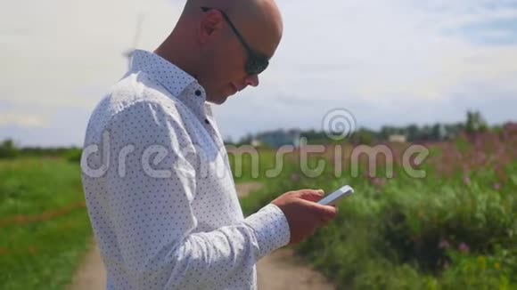 男人用和滚动手机背景下的一个乡间小路夏天中弹视频的预览图