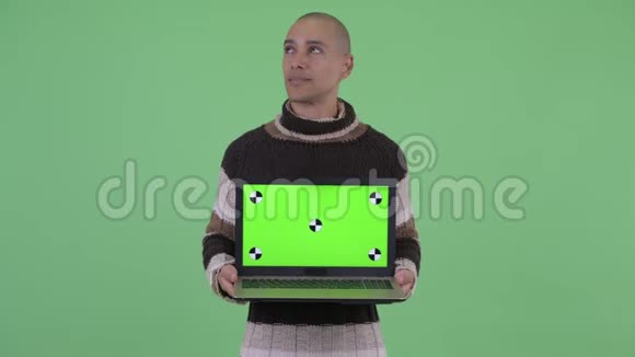 快乐的秃头多民族男人一边看着笔记本电脑一边说话视频的预览图