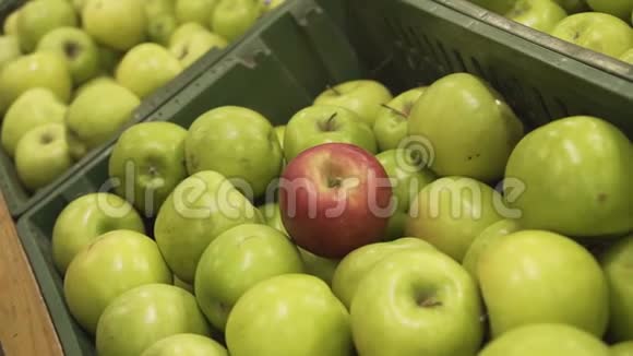 在一家超市的熟食店里在出售的青苹果中挑选红苹果的女性手特写视频的预览图
