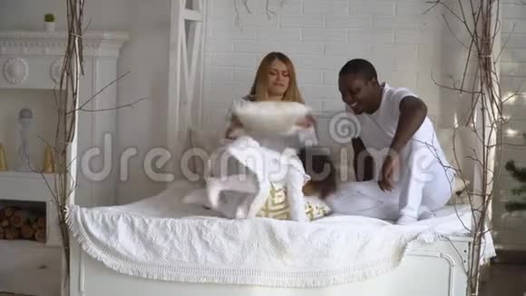 快乐混血家庭妈妈非洲爸爸和小女儿在床上玩枕头大战多民族青年视频的预览图