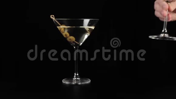 豪华马提尼手把一杯带橄榄的甜马提尼放在黑色的桌子上背景是黑色的佛蒙特州视频的预览图