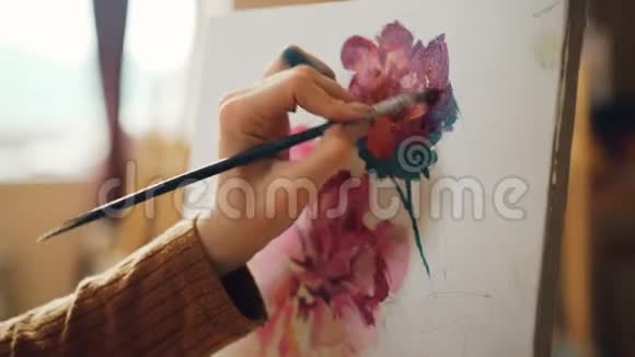 她手里拿着画笔画着花画着美丽的静物画在车间里工作视频的预览图