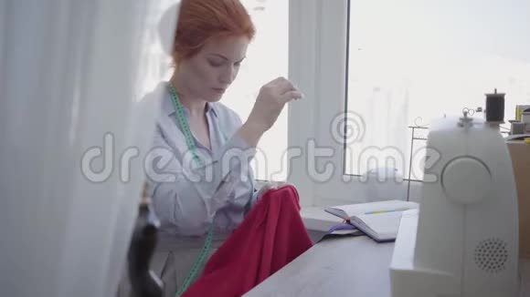 成功的女人在车间的桌子上缝纫裁缝工作勤奋细心爱好和工作缝纫视频的预览图