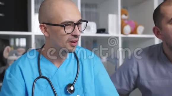 两名男性医生在辛苦工作一天后在医生休息室里缓解压力酒精视频的预览图