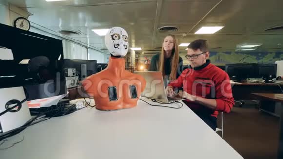 年轻的工程师正在操纵一个半机器人移动它的面部器官视频的预览图