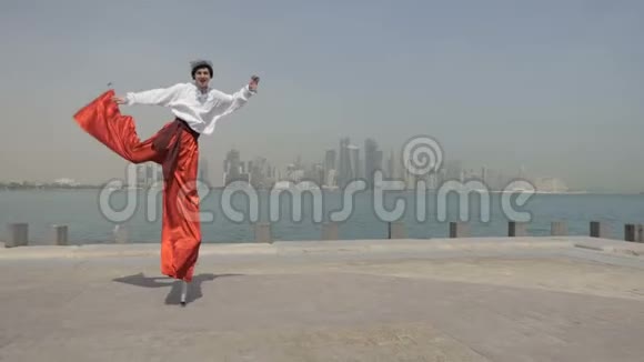 在迪拜穿着科萨克西装的快乐男人在海上码头上跳一个高跷视频的预览图