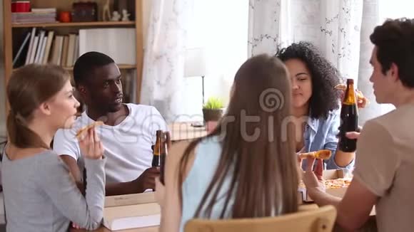 快乐的多种族朋友吃比萨饼喝啤酒谈论比萨饼视频的预览图