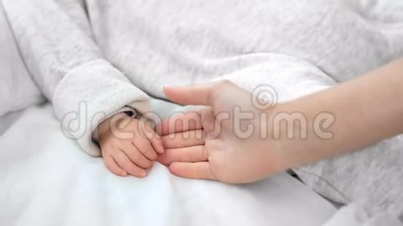 贴心关爱的妈妈手抚摸可爱的小宝宝手臂感受爱与温柔视频的预览图